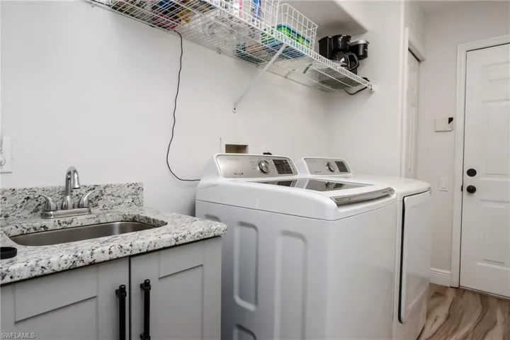 Laundry area featuring a sink, washer and dryer, and light wood finished floors