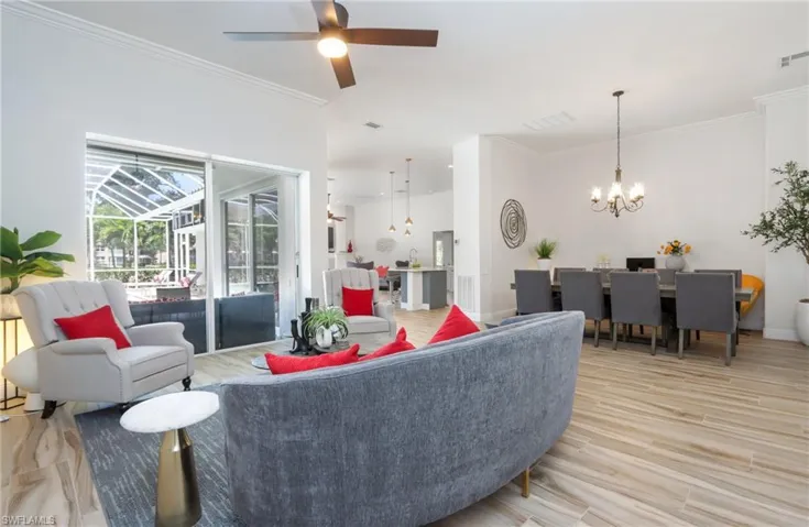 Living room with a chandelier, ceiling fan, crown molding, light wood finished floors, and baseboards