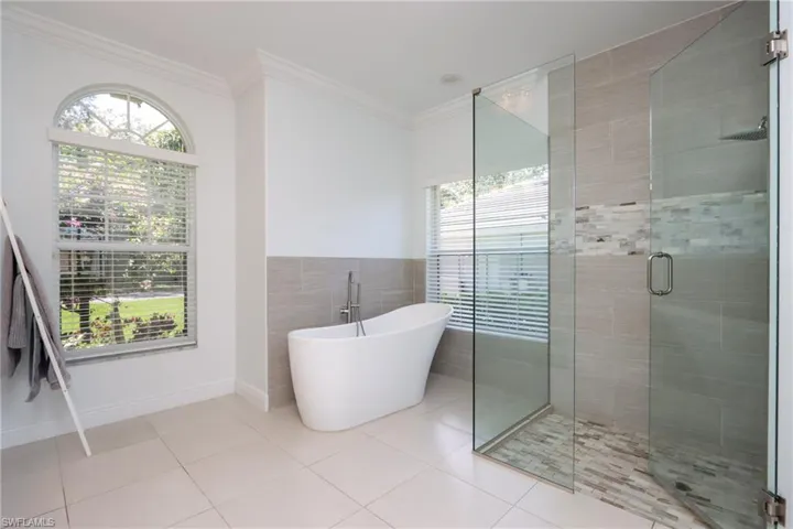 Full bath with a shower stall, plenty of natural light, a freestanding tub, tile patterned floors, and crown molding