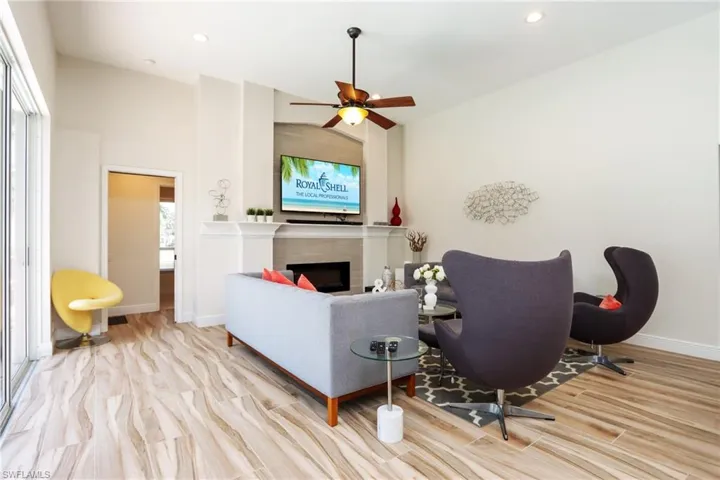 Living area featuring baseboards, wood finished floors, a fireplace, vaulted ceiling, and recessed lighting