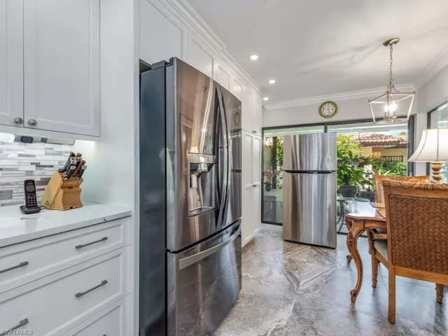 Kitchen with stainless steel refrigerator with ice dispenser, freestanding refrigerator, white cabinets, a barn door, and decorative light fixtures