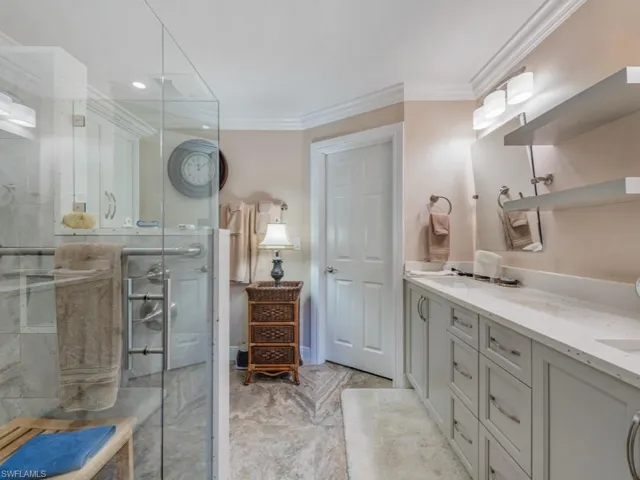 Bathroom featuring double vanity, a shower stall, ornamental molding, and recessed lighting