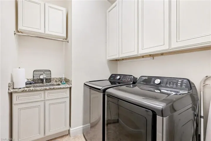 Laundry room with cabinet space, separate washer and dryer, and light tile patterned floors