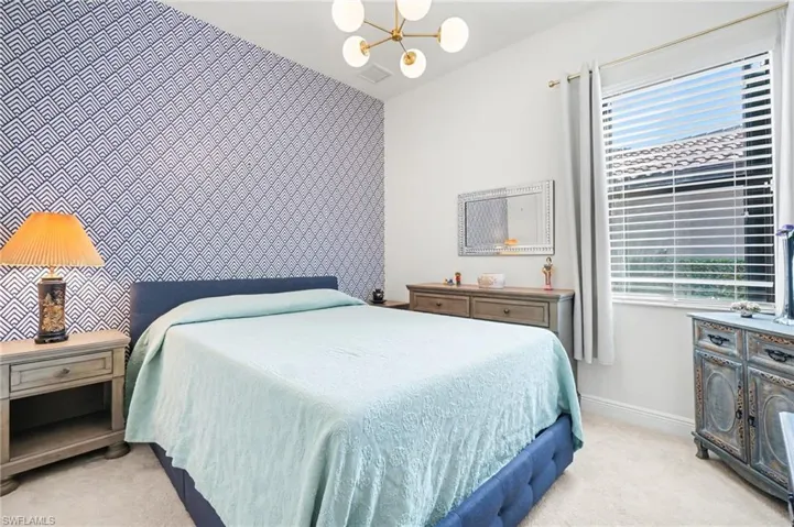 Bedroom featuring an accent wall, light carpet, a chandelier, and wallpapered walls