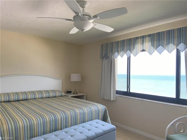 Bedroom featuring baseboards, ceiling fan, a water view, carpet, and a textured ceiling