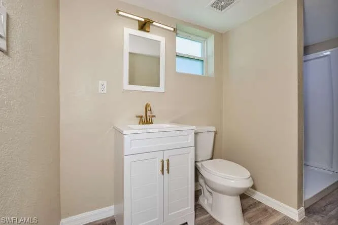 Bathroom featuring hardwood / wood-style floors, toilet, and vanity