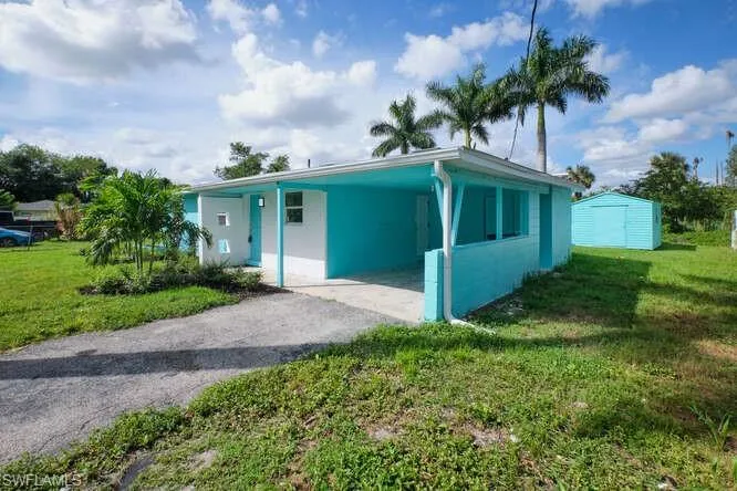 View of front facade featuring an outbuilding, a carport, and a front yard