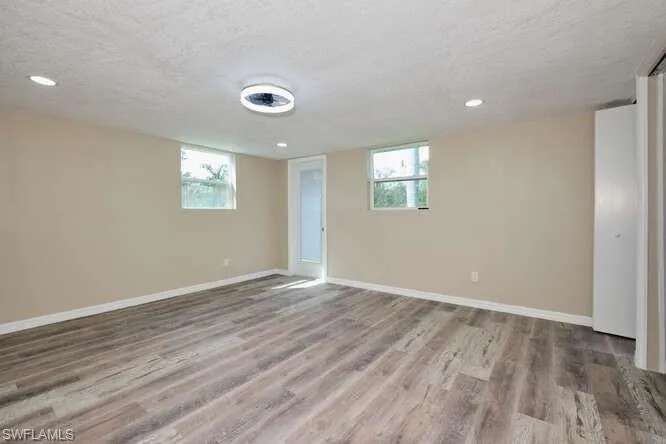 Spare room with hardwood / wood-style flooring, a textured ceiling, and a healthy amount of sunlight