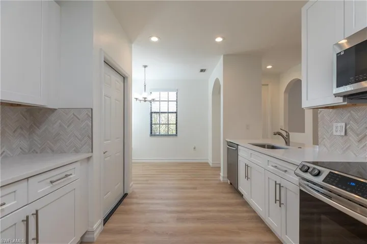 Kitchen with stainless steel appliances, tasteful backsplash, white cabinetry, and recessed lighting