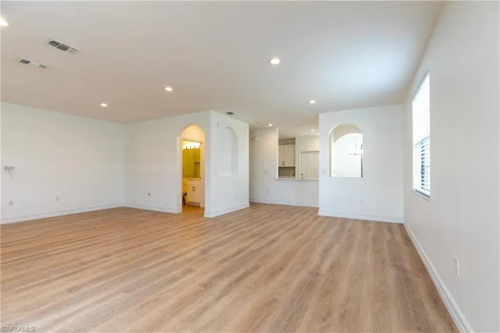 Living room featuring arched walkways, light wood finished floors, and recessed lighting