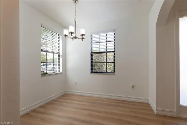 Breakfast area with a chandelier, light wood-style flooring, and arched walkways