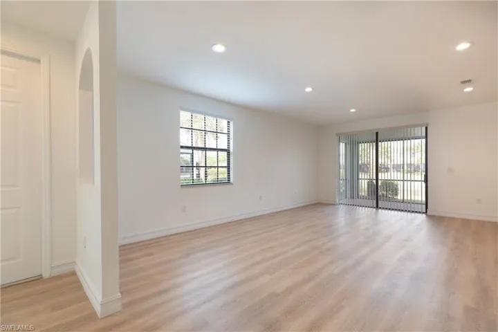 Living room featuring light wood-style flooring, recessed lighting, and arched walkways
