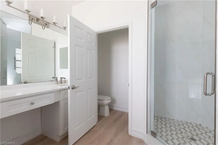 Master bathroom with a marble finish shower, light wood-style finished floors, and separate wc