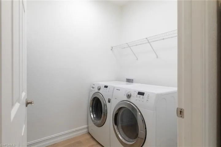 Laundry with separate washer and dryer and light wood-style flooring