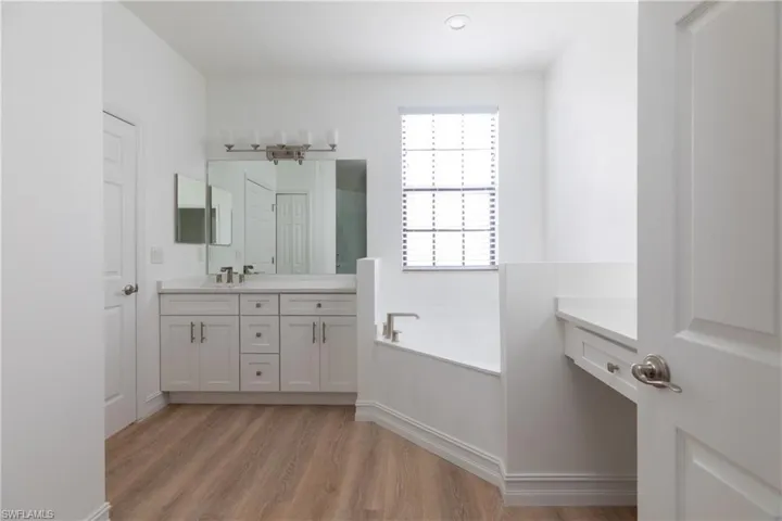 Master bathroom with a bath, double vanity, light wood-style finished floors, and a shower with shower door