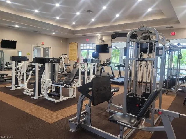 Exercise room featuring crown molding, carpet floors, recessed lighting, and a raised ceiling