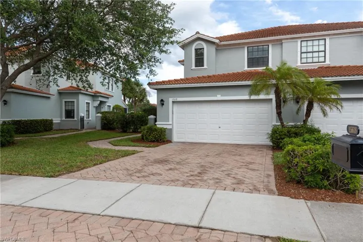 Mediterranean / spanish home featuring decorative driveway, stucco siding, a tile roof, an attached garage, and a front lawn