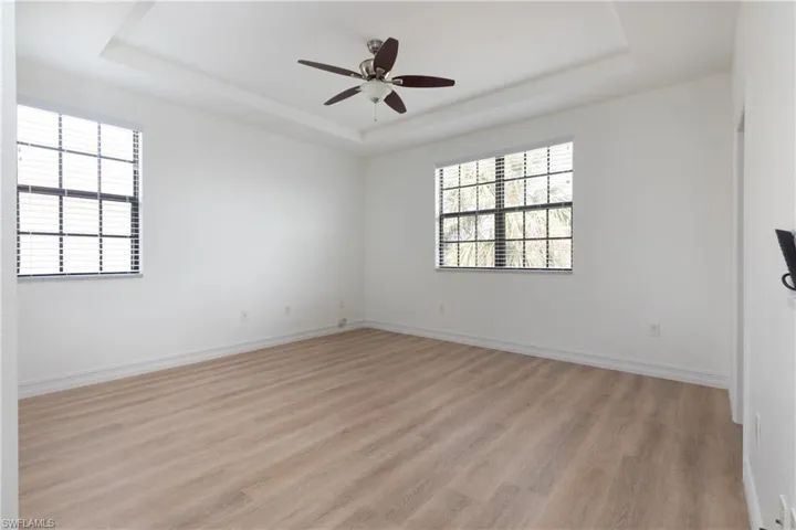 Master bedroom featuring a tray ceiling, light wood-style flooring, and ceiling fan