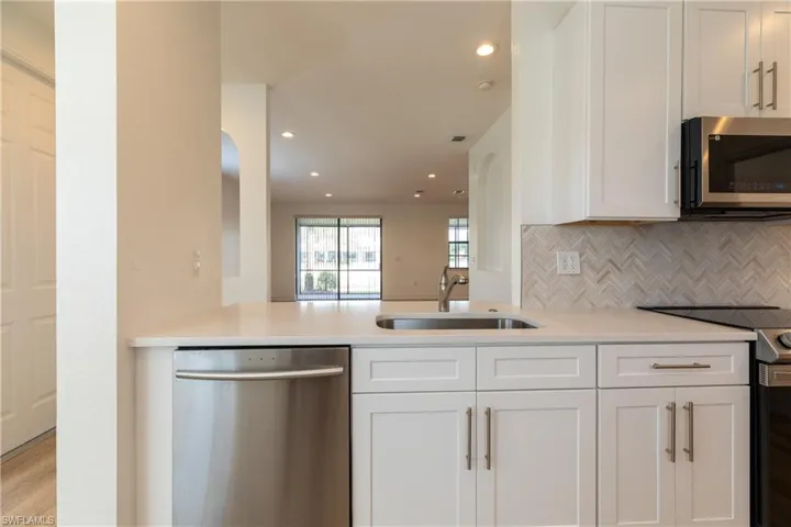 Kitchen with stainless steel appliances, tasteful backsplash, arched walkways, white cabinets, and recessed lighting