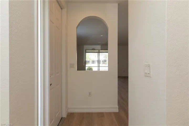Hallway featuring light wood-style flooring and arched walkways