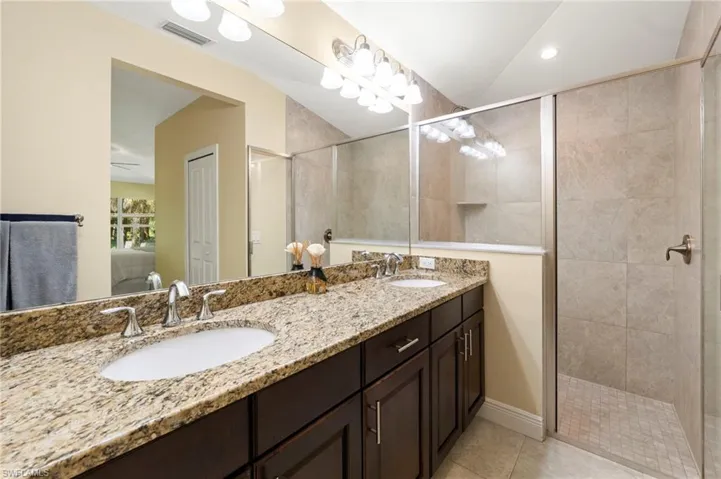 Dual vanity with stone countertop, dark wood-finish cabinetry, and chrome fixtures
