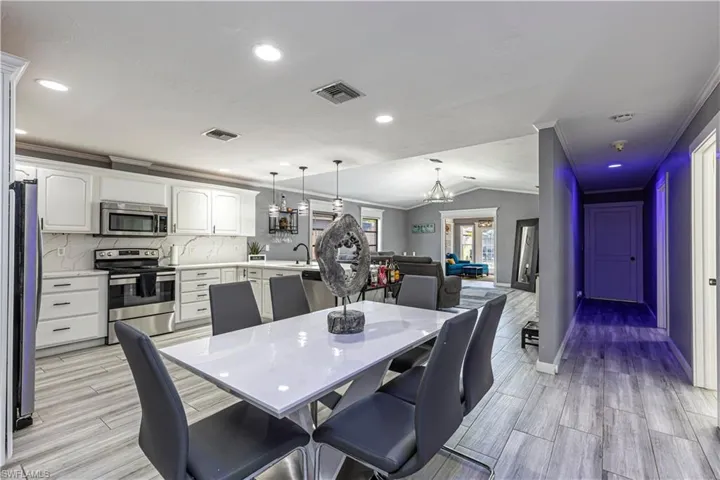 Dining room with vaulted ceiling, wood finish floors, a chandelier, recessed lighting, and crown molding