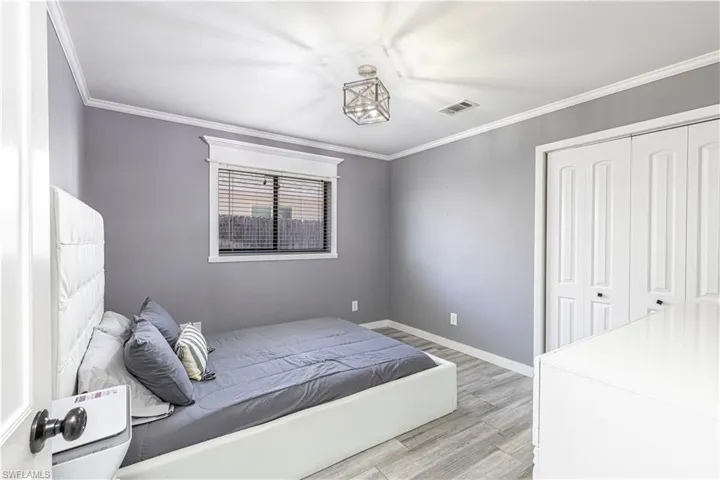 Bedroom featuring light wood-style flooring, ornamental molding, and a closet