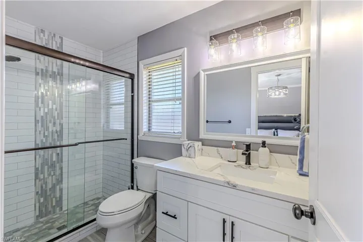 Full bath featuring ensuite bath, vanity, and a shower stall