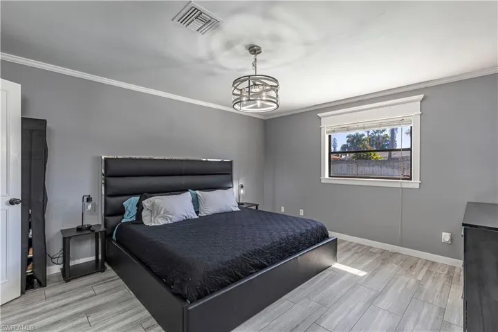 Bedroom featuring crown molding, wood tiled floors, and a chandelier