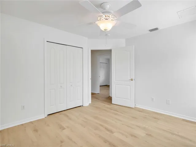 Room featuring wood-finish flooring, white walls, and a ceiling fan with integrated lighting