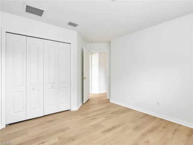 Room featuring wood-finish flooring, white baseboards, and a four-panel bi-fold closet door