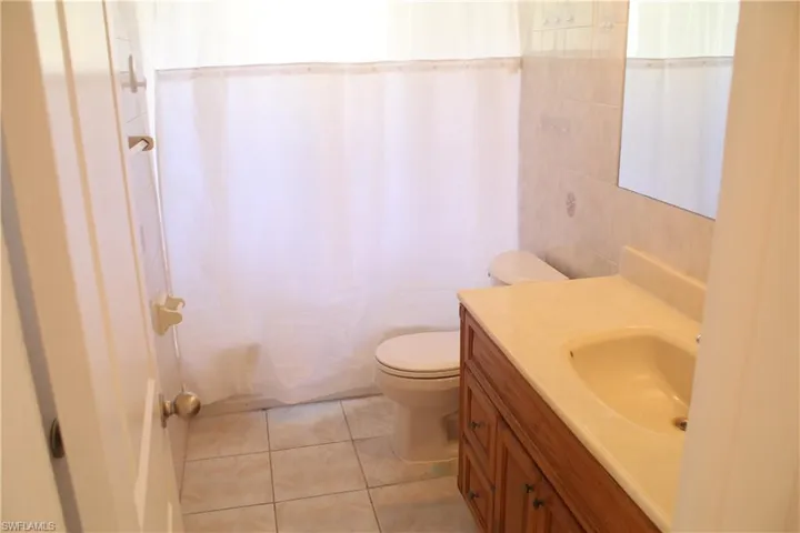 Bathroom featuring vanity, light tile patterned flooring, tile walls, and shower / bath combo