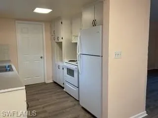 Kitchen with light countertops, white appliances, white cabinets.  Luxury Vinyl Flooring