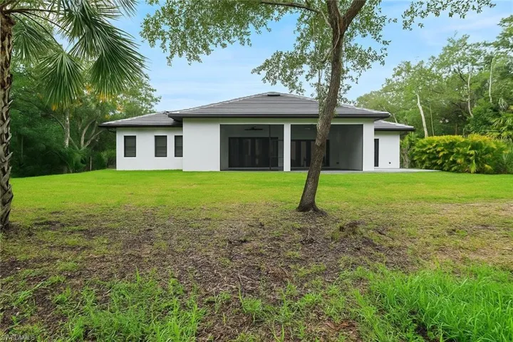 Back of house featuring stucco siding, a lawn, a ceiling fan, and a sunroom