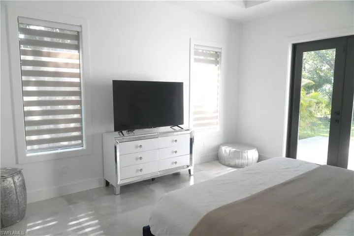 Bedroom featuring multiple windows, access to outside, and concrete floors