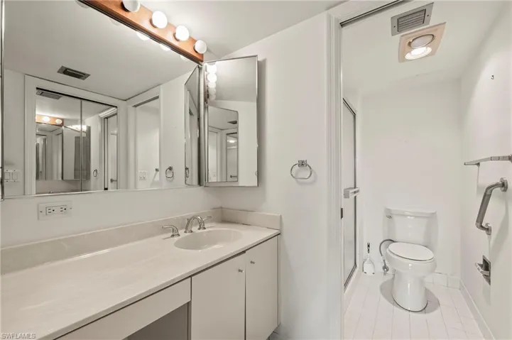 Bathroom featuring an enclosed shower, vanity, toilet, and tile patterned flooring