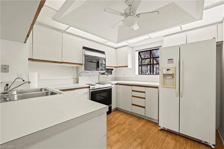 Kitchen with white appliances, white cabinetry, light hardwood / wood-style floors, sink, and ceiling fan