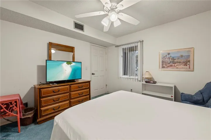 Carpeted bedroom with ceiling fan and a textured ceiling