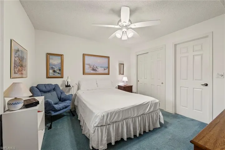 Carpeted bedroom featuring ceiling fan, a closet, and a textured ceiling
