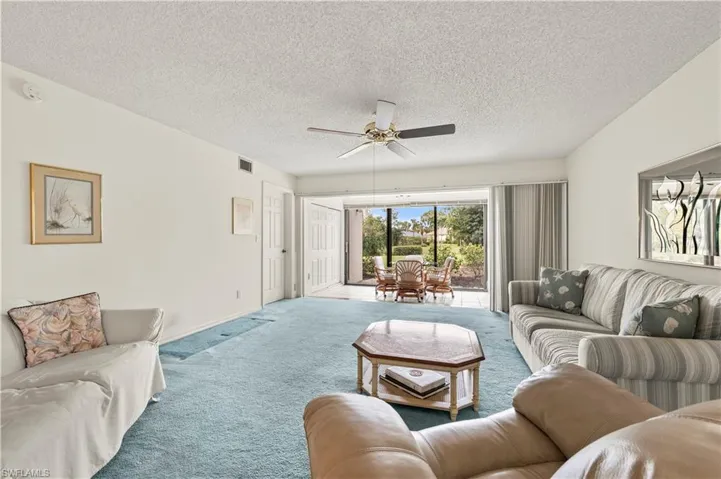 Living room featuring ceiling fan, a textured ceiling, and carpet
