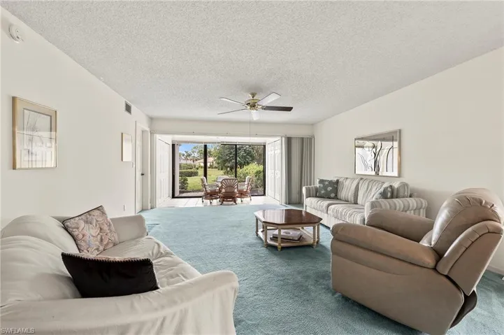 Living room featuring carpet floors, ceiling fan, and a textured ceiling