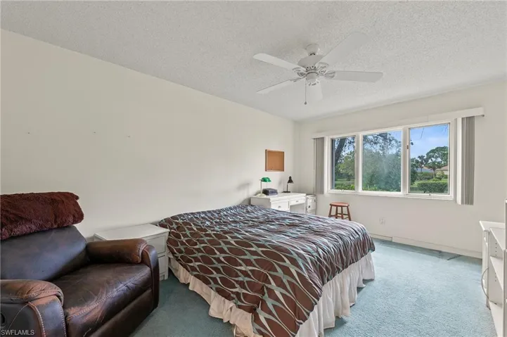 Bedroom with ceiling fan, a textured ceiling, and light carpet