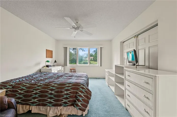 Bedroom featuring a textured ceiling, ceiling fan, a closet, and light colored carpet
