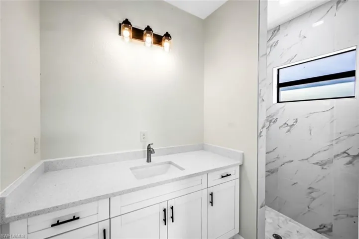 Full bathroom featuring vanity and a marble finish shower