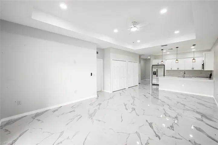 Unfurnished living room featuring a tray ceiling, ceiling fan, and recessed lighting