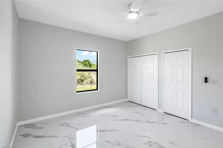 Unfurnished bedroom featuring multiple closets, a ceiling fan, and light marble finish flooring