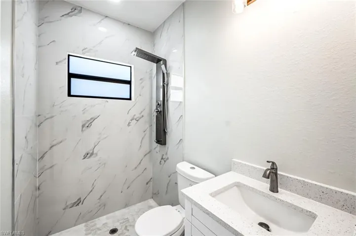 Full bathroom featuring vanity and a marble finish shower