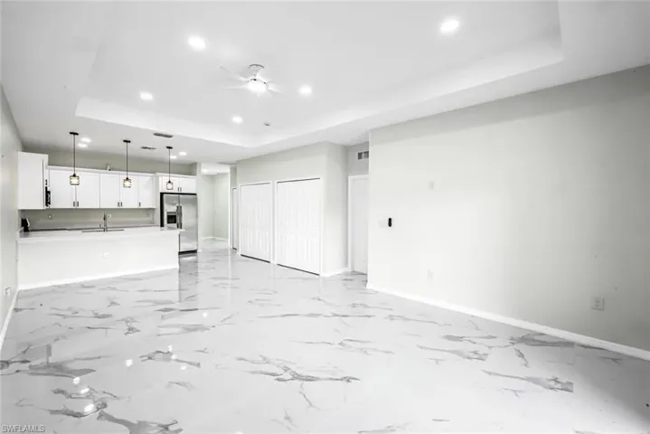 Unfurnished living room featuring a raised ceiling, recessed lighting, and ceiling fan