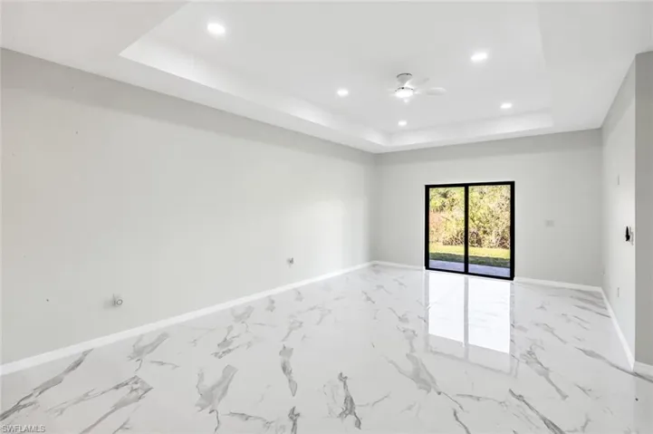 Unfurnished room with recessed lighting, a ceiling fan, light marble finish floors, and a raised ceiling