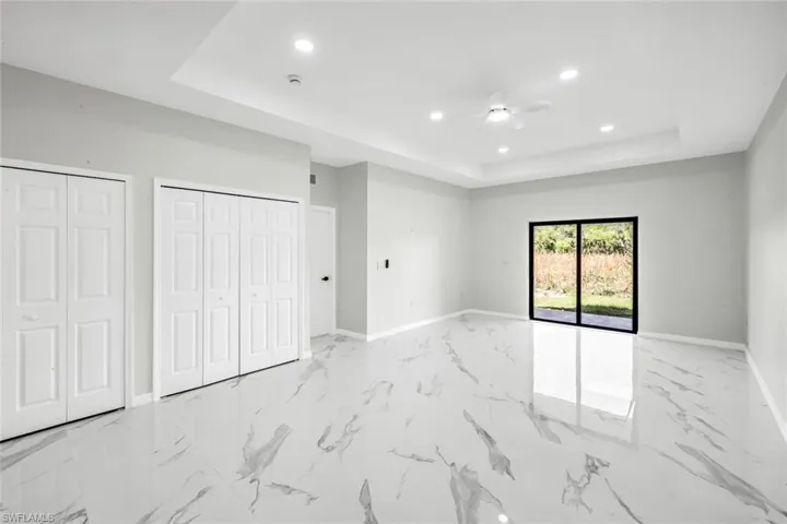 Unfurnished bedroom with recessed lighting, multiple closets, a raised ceiling, and ceiling fan